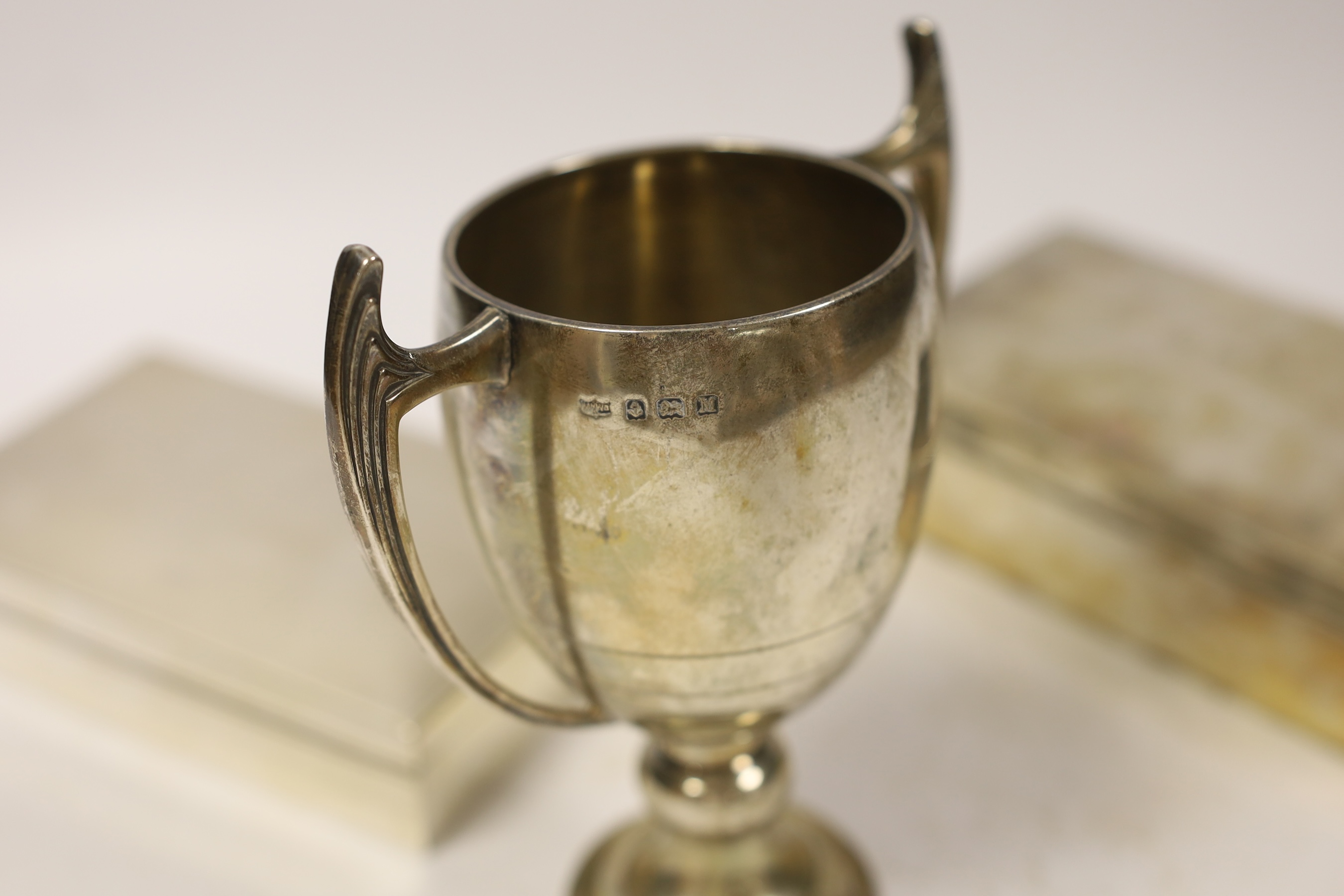 A 1930's Art Deco silver two handled presentation trophy cup, by Mappin & Webb, 15.6cm, and two silver mounted rectangular cigarette boxes.